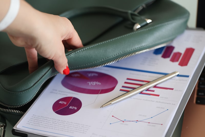 Grundstuecksmarktberichte Eine Frau öffnet eine grüne Tasche und entnimmt einen Stapel Blätter mit Statistiken